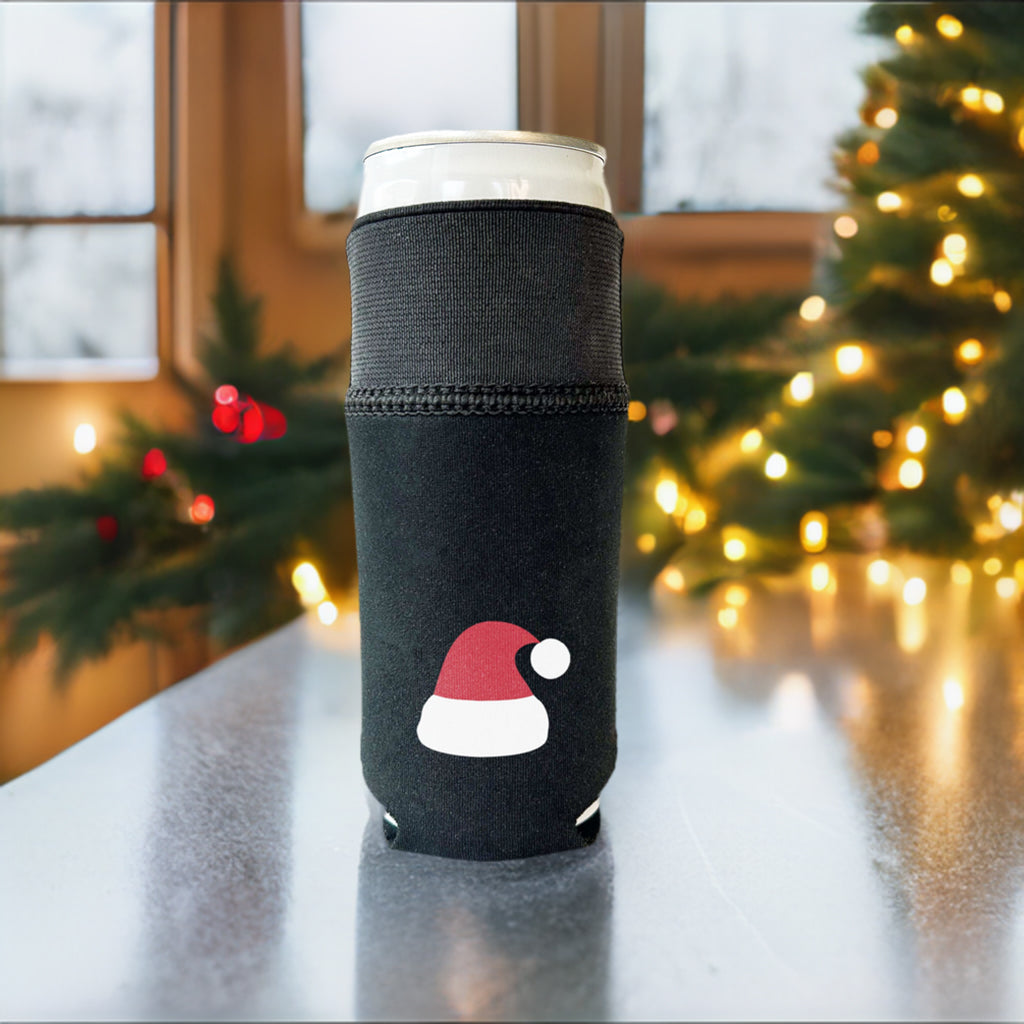All black Candabra drink sleeve with a red and white Santa hat design.  Pictured on a slim 12 oz can with the elastic cuff extended.  Sitting on a table with Christmas tree in the background